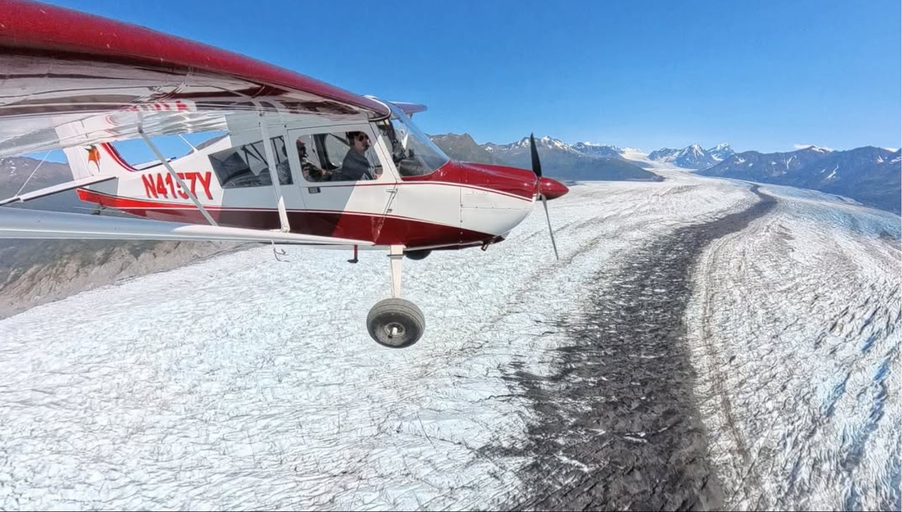 Bush aircraft flying beside a glacier in Alaska.