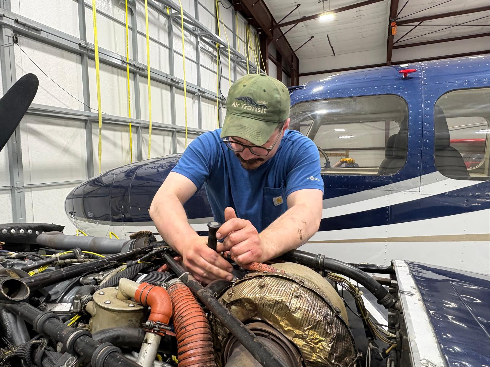 Michael Iffland working on a piston aircraft engine in a hangar.