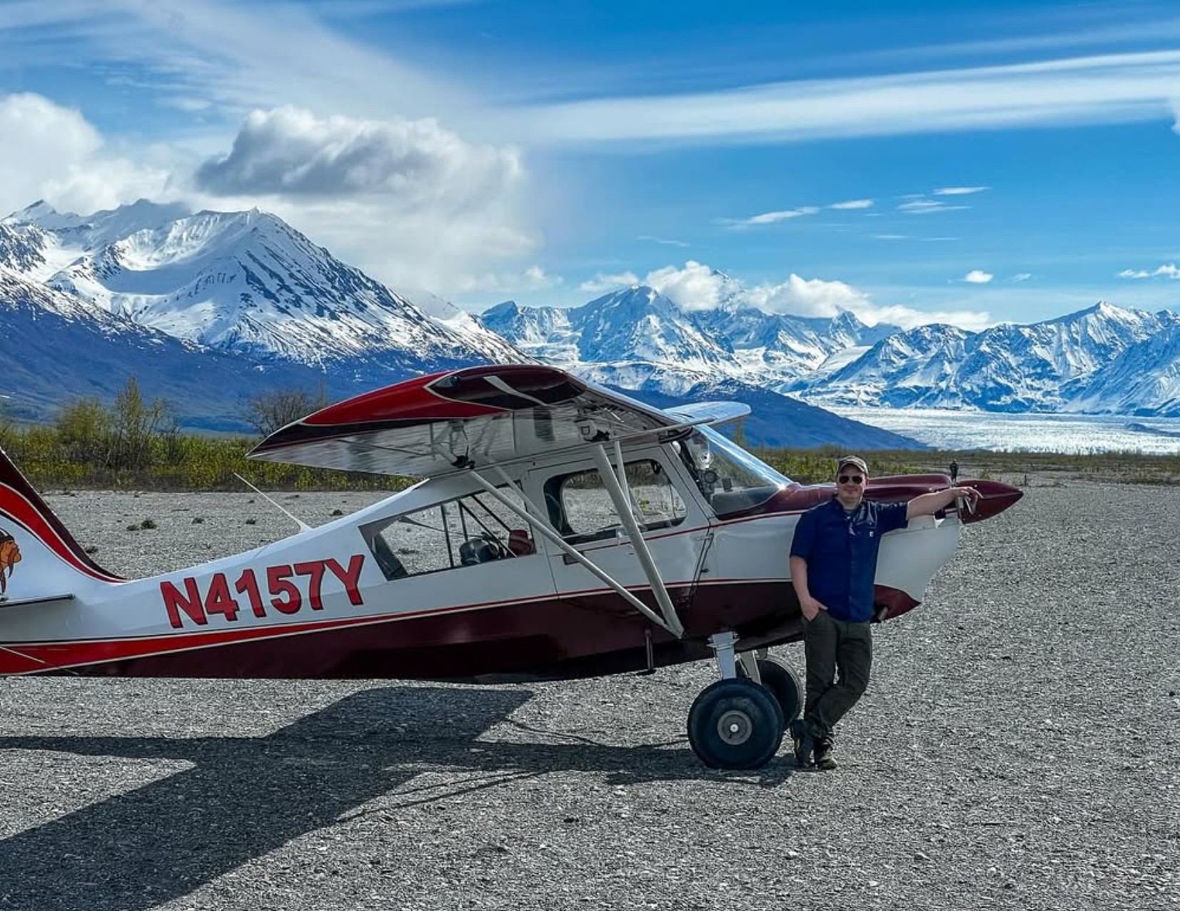 Michael Iffland standing beside a bush aircraft with Alaska mountains in the background.