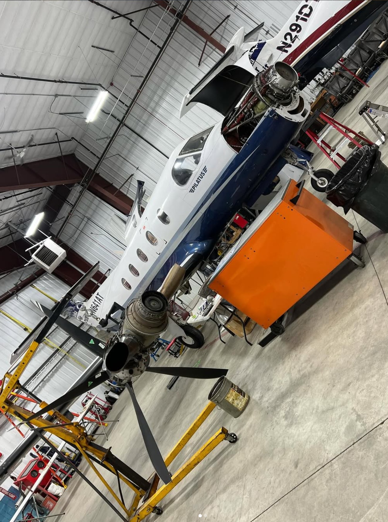 Pilatus aircraft in a hangar with engine exposed for maintenance.